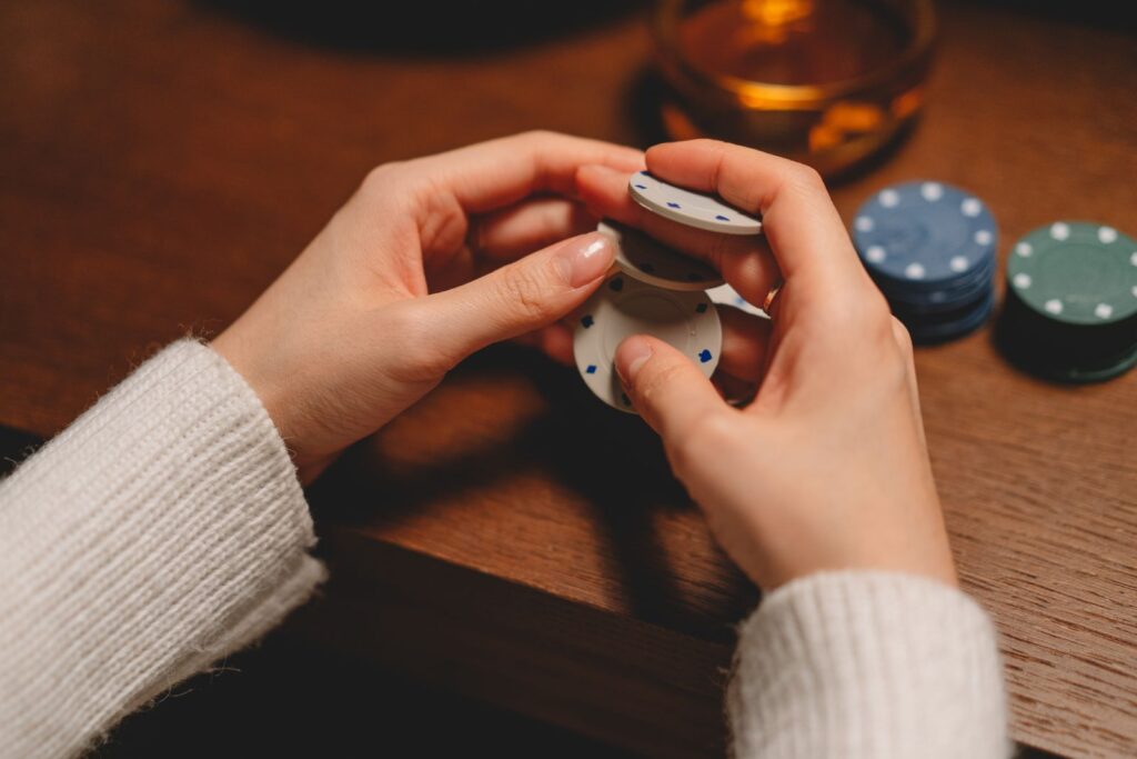 Handen met pokerfiches aan een houten tafel
