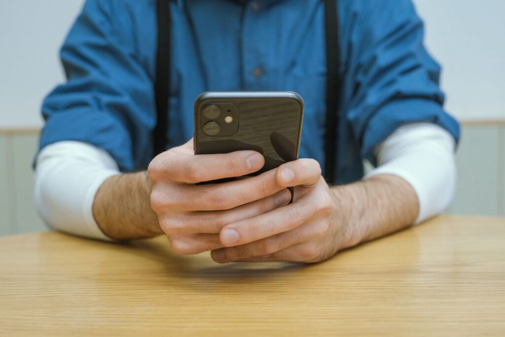 Iemand houdt een smartphone boven een houten tafel