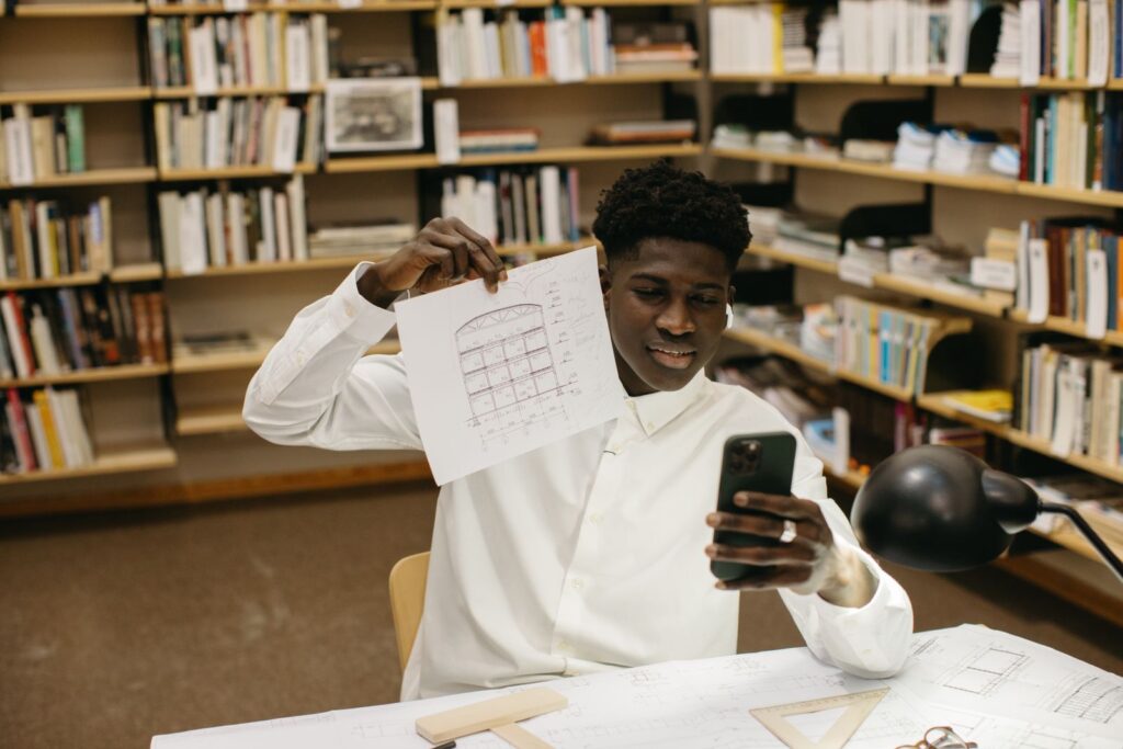 Man met een telefoon en een bouwtekening in een werkruimte